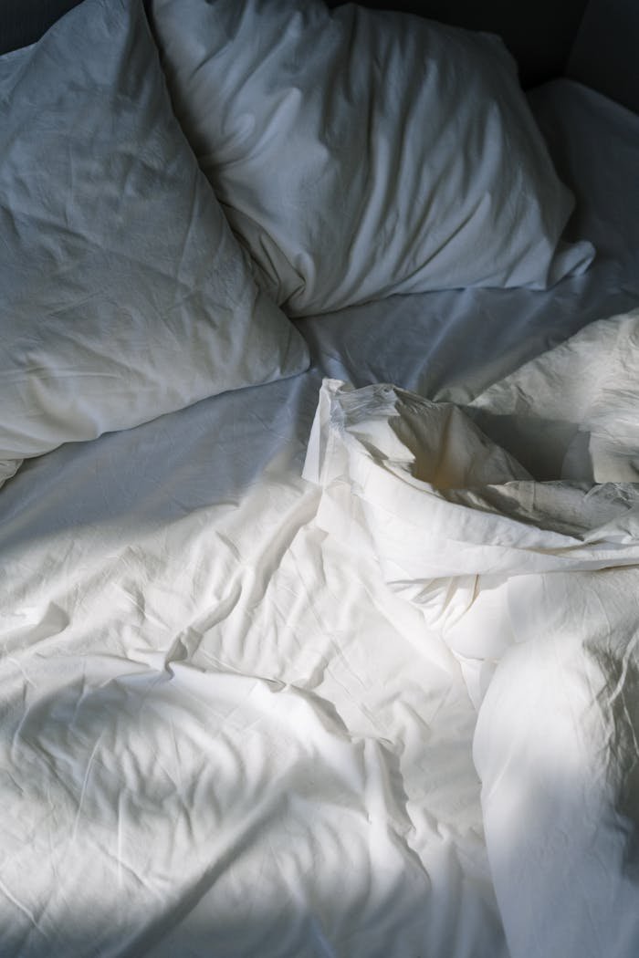 Services-01 A cozy, inviting bed with white linens lit by morning sunlight, creating a restful atmosphere.