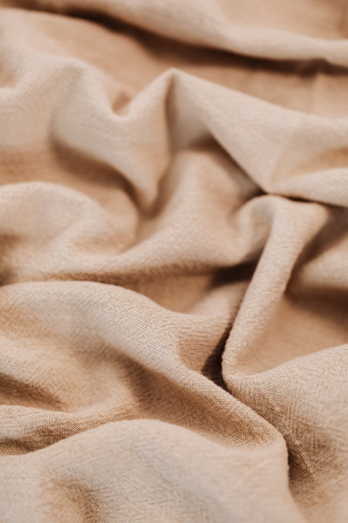 A close-up shot of textured beige fabric with natural wrinkles and folds.