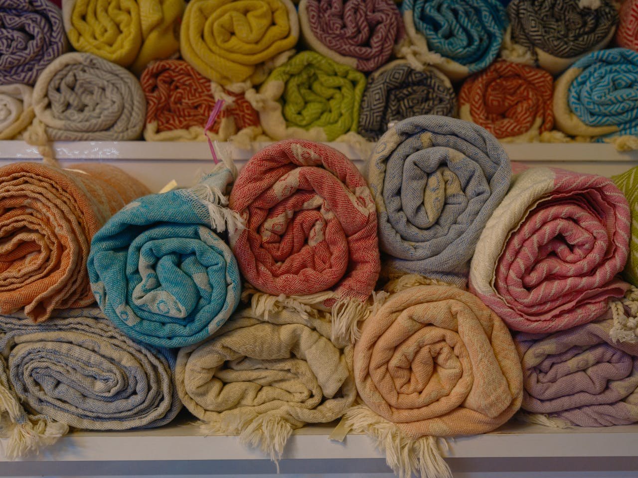 A close-up of rolled colorful blankets stacked neatly in an indoor display.