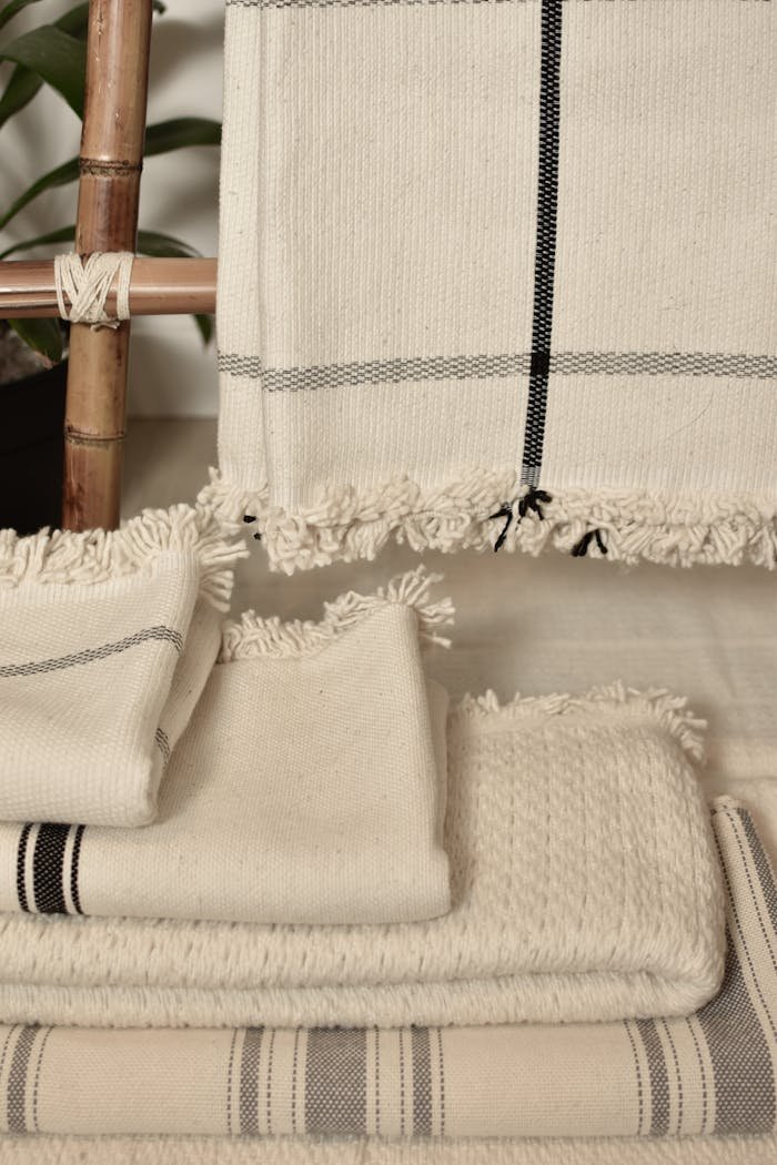 Close-up of neatly stacked neutral cotton and linen textiles, showcasing texture and woven patterns.